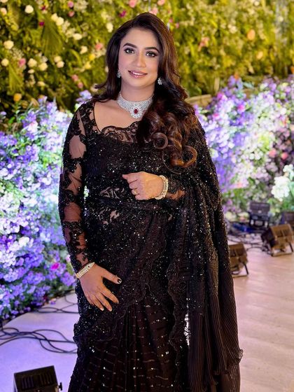 A glamorous reception look featuring a stunning black sequined saree and a diamond choker.