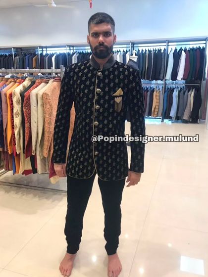 A client trying on a black velvet Jodhpuri jacket with gold detailing in my store. This is a classic piece that combines royal style with a modern fit.