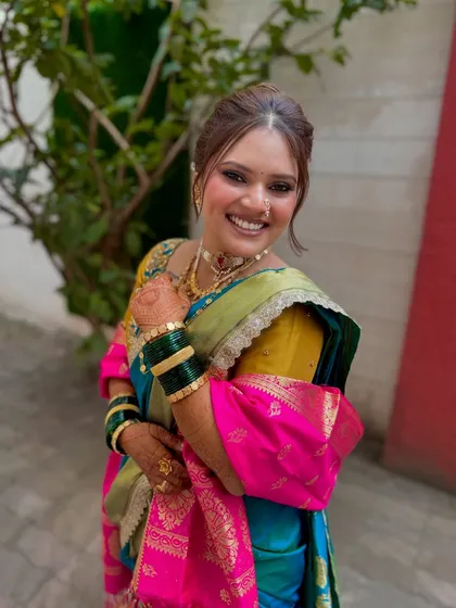 A joyful portrait of the bride. The soft nude tones of her makeup look beautiful with the vibrant colors of her teal and pink saree.