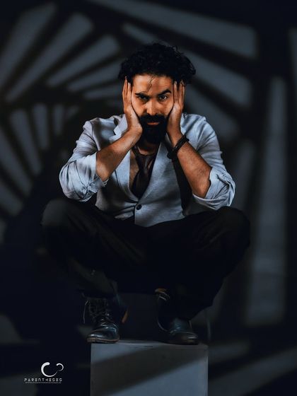 A moment of raw emotion. Framing the face with his hands draws the viewer's attention to his expressive eyes, creating a powerful and vulnerable portrait.