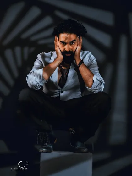 A moment of raw emotion. Framing the face with his hands draws the viewer's attention to his expressive eyes, creating a powerful and vulnerable portrait.