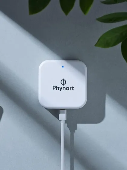 A creative composition for a Phynart smart device. The play of light and shadow from the leaves adds an organic, gentle touch to a piece of technology, making it feel more at home.