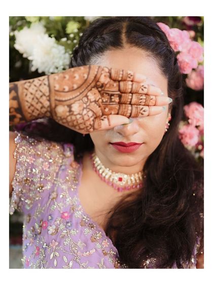 A bride peeking through her fingers, her hand adorned with intricate henna. A playful and beautiful portrait.