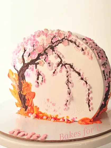 A stunning cake featuring a hand-painted cherry blossom tree. The delicate pink blossoms are piped with buttercream, creating a beautiful and artistic centerpiece.