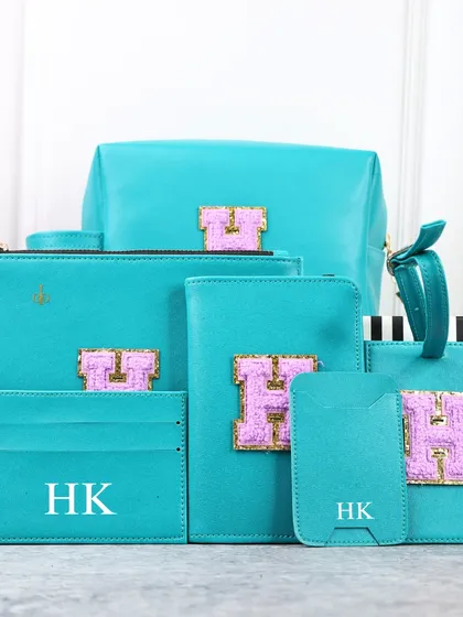This vibrant turquoise travel set is personalized with a pink and glitter chenille initial patch. The set includes multiple pouches, a passport cover, and card holders for ultimate organization.
