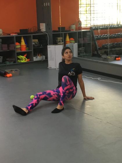 A student uses a tennis ball for self-myofascial release on her glutes, a technique taught in our mobility workshops.