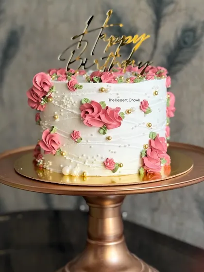 A classic birthday cake design with delicate pink floral piping and pearl details. This timeless style is always a beautiful choice.