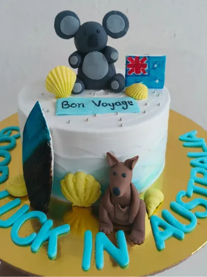 A "Bon Voyage" cake for someone moving to Australia, featuring a fondant koala, kangaroo, and surfboard.