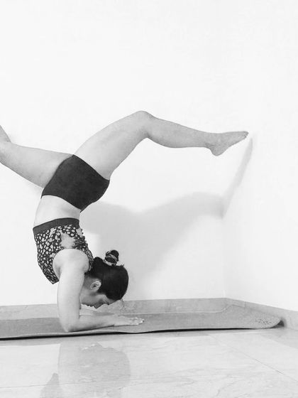 A wider leg variation in the wall-assisted Pincha. This helps open the hips while still upside down.