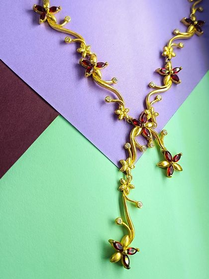 Another angle of the gold-plated red floral necklace, showing how the design gracefully drapes around the neck.