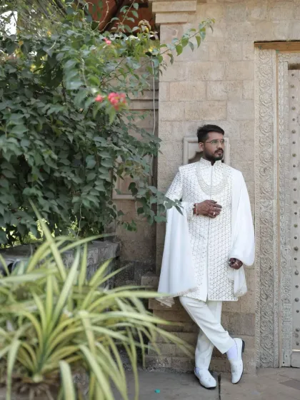 This client chose a regal white sherwani featuring intricate embroidery and dramatic draped sleeves. It's a powerful statement piece designed for a groom who wants a touch of royal flair.