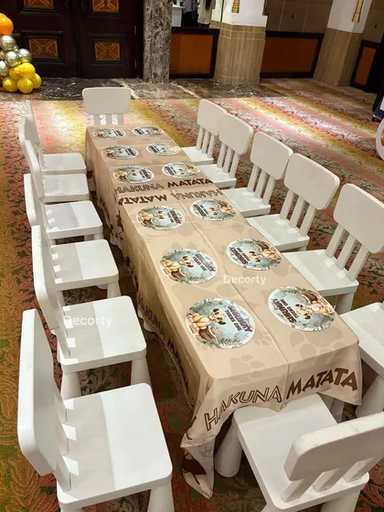 A dedicated seating area for the little guests. The table is covered with a "Hakuna Matata" tablecloth, and the child-sized chairs make it a comfortable spot for them.