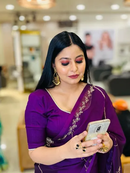 A candid shot of a client in a purple saree. Her makeup is elegant and sophisticated, perfect for a formal event.