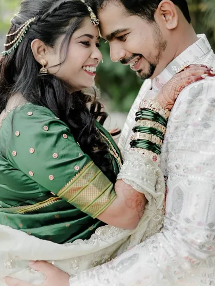 A romantic and happy couple portrait from their engagement. The bride looks beautiful in her green saree, sharing a joyful moment with her fiancé.