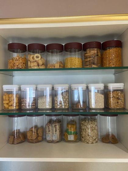 This pantry is stocked with a variety of snacks and dry goods, all decanted into clear containers. This system is perfect for families, as it makes it easy for everyone to see the available options.