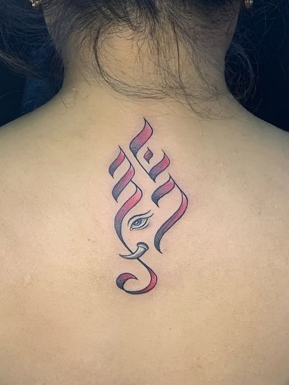 A stylized Ganesha tattoo on the back, created with calligraphic lines and a hint of color. This minimalist design is a modern tribute to the deity.