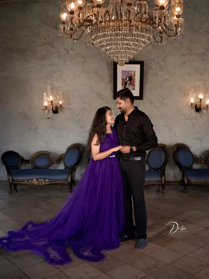 A classic pre-wedding pose in a luxurious room. The purple trail gown looks stunning against the backdrop of chandeliers and vintage furniture.