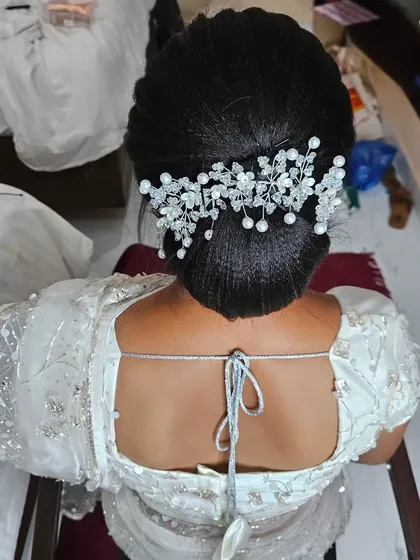A back view of a Christian wedding hairstyle, a chic and elegant updo adorned with a beautiful pearl and crystal hair accessory.