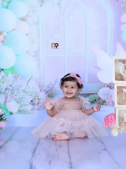 A beautiful, wide shot of the fairy-themed setup, with a little girl sitting among flowers, balloons, and teddy bears. The "ONE" blocks add a celebratory touch for a first birthday.