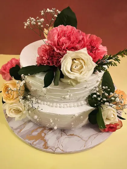 There's something magical about creating a cake for a wedding. This two-tiered beauty, adorned with fresh roses and carnations, is designed to be an elegant centerpiece. I work with you to ensure your wedding cake is as memorable as the day itself.
