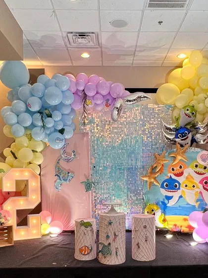 The complete stage for the pastel Baby Shark party, featuring multiple backdrops, foil balloons, and character props.