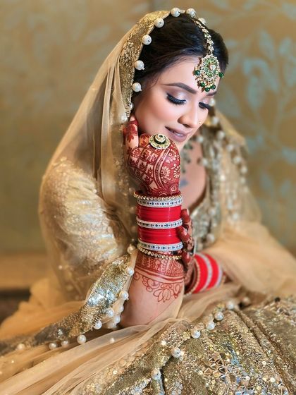 A candid, shy pose from the bride, highlighting the intricate henna and the beautiful pearl detailing on the dupatta.
