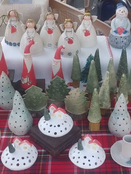 My Christmas village on display at The Lil Flea market. The collection includes Santa and angel figurines, ceramic trees, and glowing snow-covered tealight holders.
