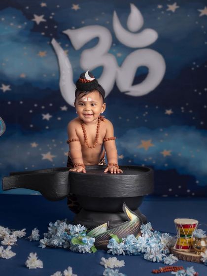 A happy little Shiva smiles brightly, standing in front of the Om symbol, ready to celebrate Shivratri.