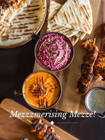 A mesmerizing mezze platter. This overhead shot shows our colourful hummus dips, grilled chicken skewers, and fresh pita bread, a highlight of our Mediterranean menu.