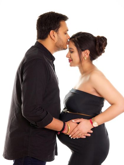 A sweet and intimate couple's portrait. The all-black outfits create a chic, coordinated look against the clean white background.