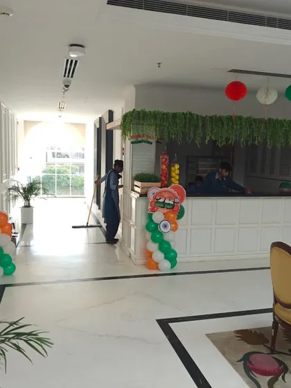 This hotel lobby is decorated with subtle patriotic touches, including tricolor balloon pillars and green foliage with paper lanterns over the reception desk. It creates a welcoming environment for guests during national holidays.