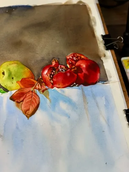 A work-in-progress shot of a still life with pomegranates. Here, the focus is on the initial layers of color and establishing the composition.