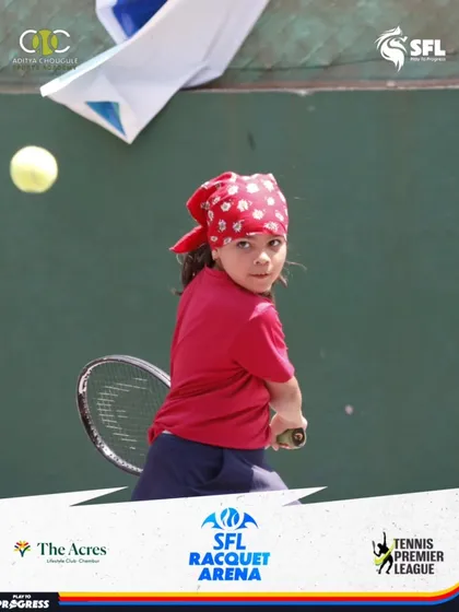 A young girl with a red bandana returns a shot with determination. We foster a fun and inclusive environment where every child can express their personality on the court.