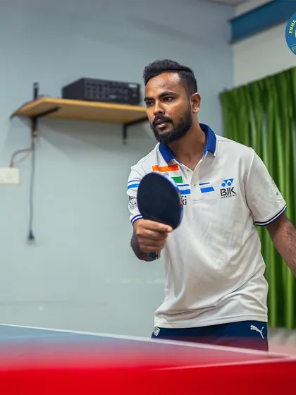 Ready to dominate the table? This player prepares to return a serve, showcasing the ready stance and focus required for high-level table tennis.