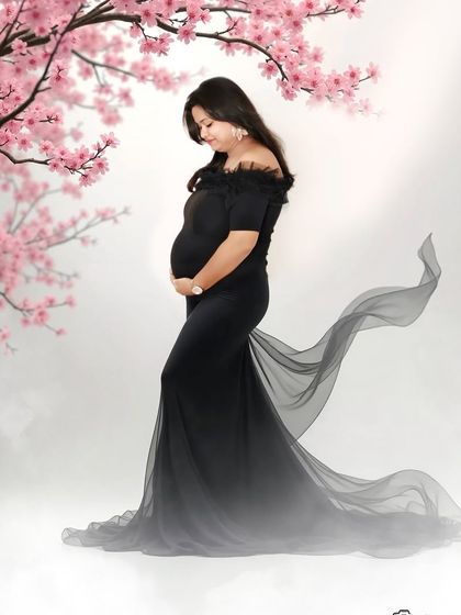 A graceful side-profile shot in a black gown with a flowing train. The cherry blossom branches add a delicate, artistic touch to this elegant studio portrait.
