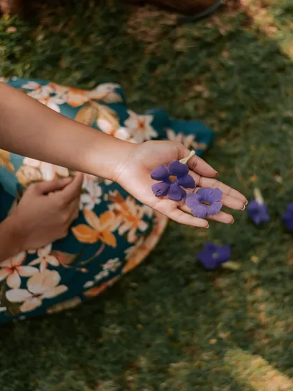 It's the small details that matter. A guest holds delicate purple flowers picked from our gardens, a simple moment of beauty and connection with the flora of Nandi Hills.