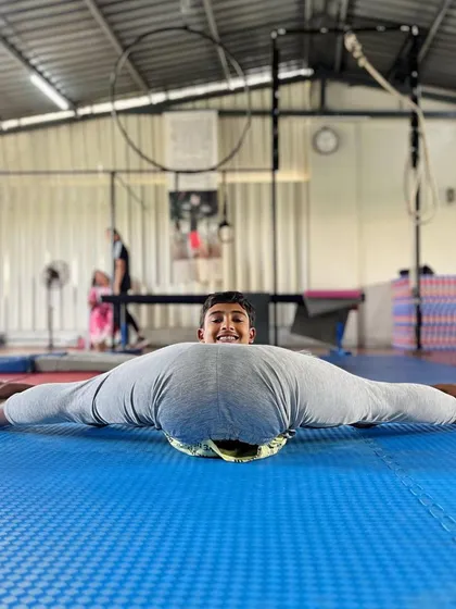 This student shows off his amazing flexibility with a full center split, using a pole for support. Our training focuses on building this level of flexibility safely and effectively.