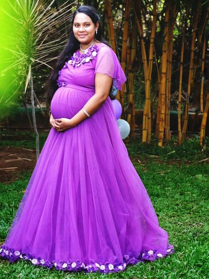 This purple maternity gown with floral shoulder details is a lovely choice for an outdoor garden photoshoot. The color stands out beautifully against the green bamboo background.