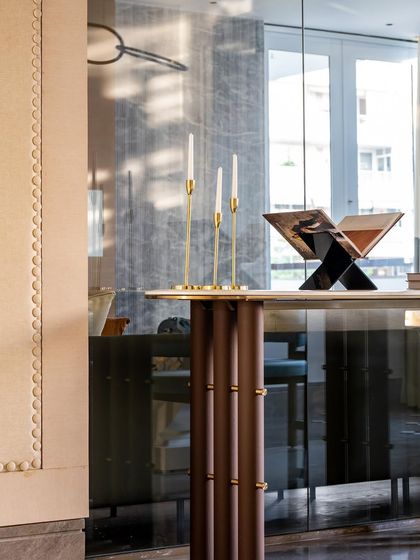 The dining area of the Auburn Home is anchored by a striking white onyx table. The sleek grey floor and blue woven leather chairs create a bold juxtaposition of color and material.