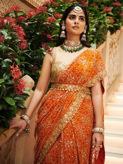A beautiful look on Isha Ambani Piramal in a vibrant orange Arpita Mehta saree. The mirror-work detailing and belted waist give this traditional garment a modern, chic twist.