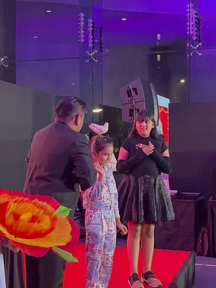 At a corporate Diwali Milan event, I invited some kids on stage to help with a grand illusion. Using large, colourful props like this giant flower makes the magic visible and exciting for everyone in the audience.