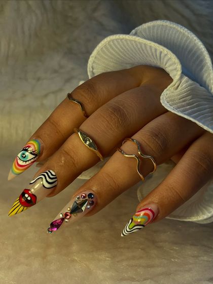 This set is pure art. We created these extra-long stiletto nails with a variety of bold, graphic designs including a rainbow eye, abstract swirls, and heavy rhinestone embellishments.