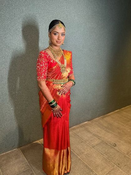 A full-length view of this bride's regal look in her red silk saree, showcasing the perfect drape and her confident posture.