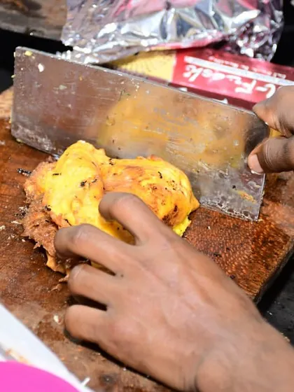 A chef chopping up a tawa dish with a large knife, a common sight at our live cooking stations where food is prepared with skill and speed.