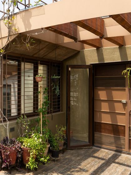 The transition from an indoor space to the terrace garden. The use of natural materials like wood for the pergola and door frames helps to create a seamless flow between the built environment and the green space outside.