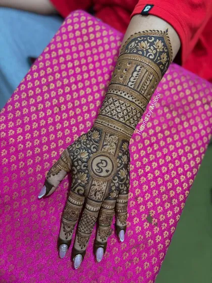 A single-arm view of the Om-themed mehendi. The symbol is placed prominently on the palm, surrounded by intricate floral and geometric patterns.