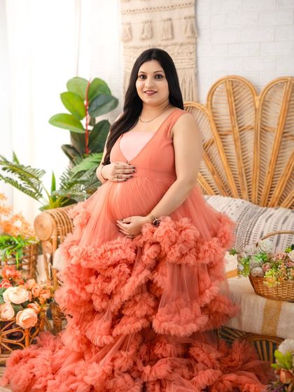 A vision in peach. This portrait highlights one of our most sought-after tulle gowns, with its voluminous ruffles creating a dramatic and romantic effect. The mother's direct gaze is both gentle and powerful.