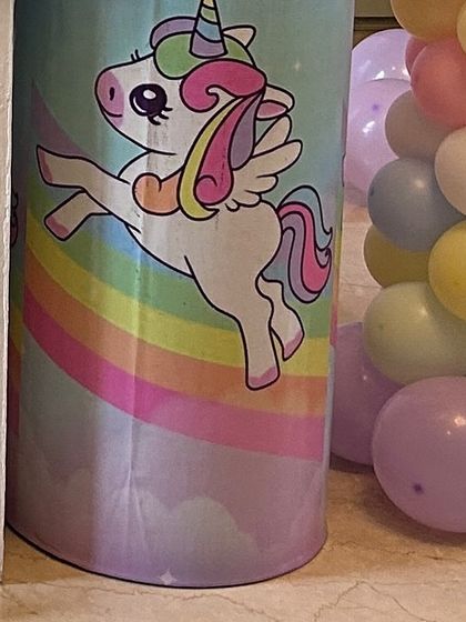 A themed pedestal wrapped in a cute unicorn and rainbow print. These custom details help to create a cohesive and immersive party environment.