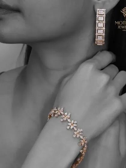 A model wears a matching set of a floral diamond bracelet and modern geometric earrings, highlighting the ability to mix and match our collections.