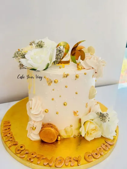 Elegance in every slice. A dreamy white and gold cake with delicate flowers and macarons.